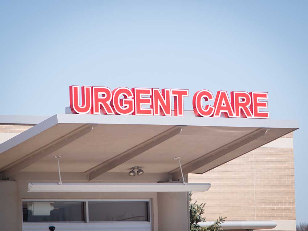 A red medical sign that reads “urgent care” outside of an urgent care facility.
