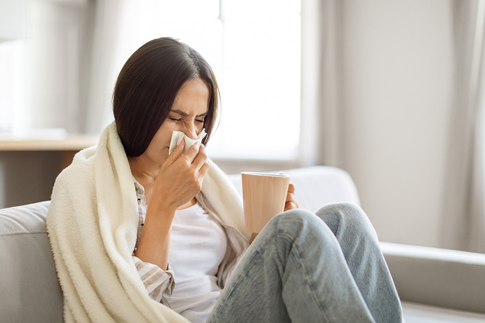 A woman with a cold or sinus infection blows her nose